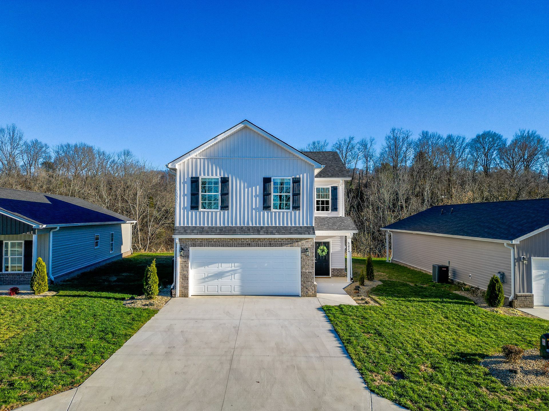 An aerial view of a house with a large garage and a driveway leading to it.