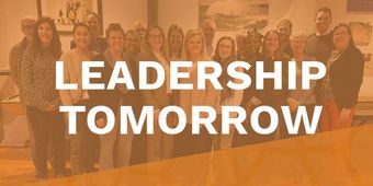 A group of people standing next to each other in a room with the words `` leadership tomorrow ''.