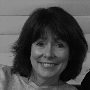 A woman with short hair is smiling in a black and white photo.
