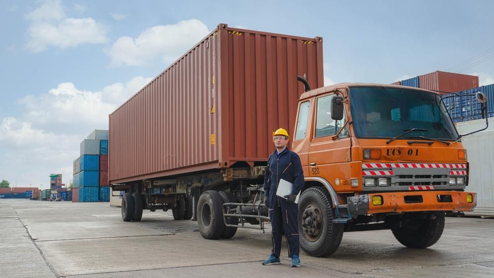 A Man Is Standing Next To A Truck In A Parking Lot — Brisbane Moving & Storage In Acacia Ridge, QLD
