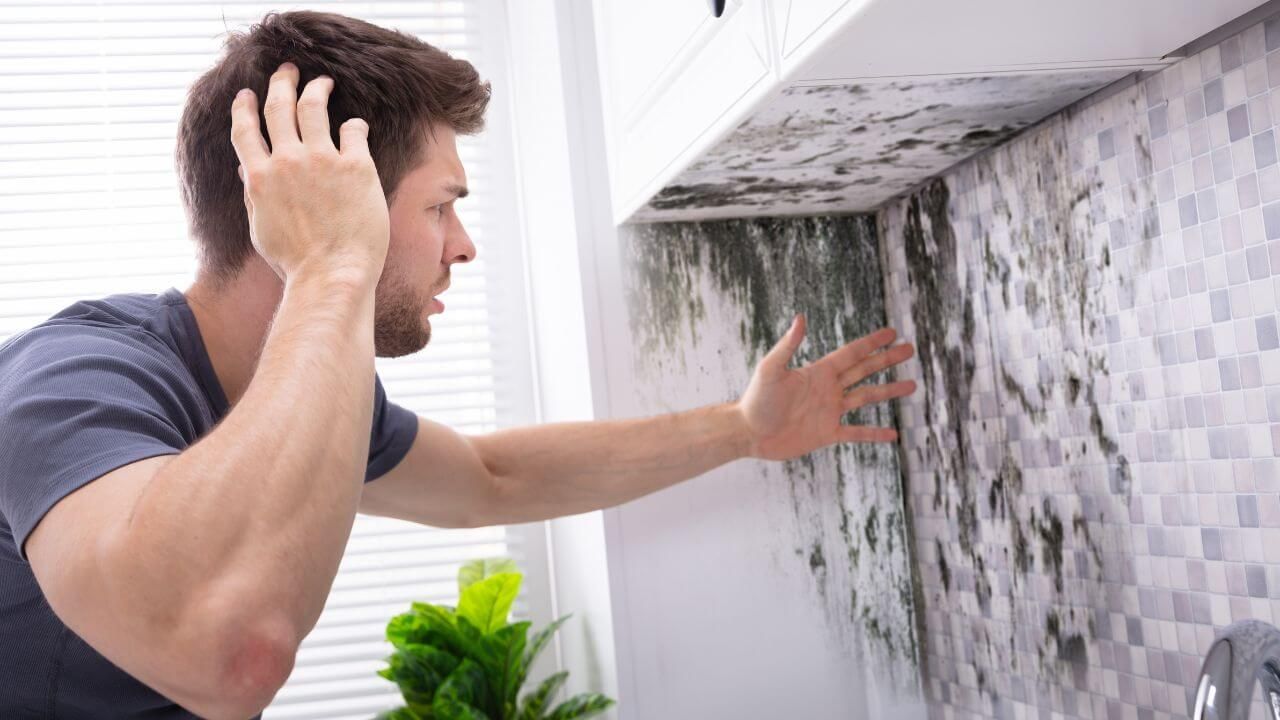 A man standing in front of a sink covered in mold.