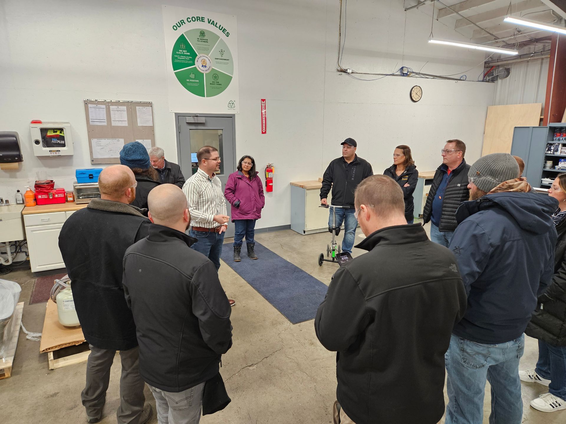 A group of individuals on a tour standing around a speaker.