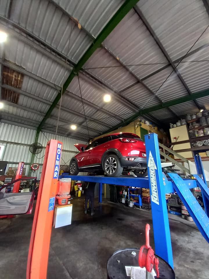 A Red Car is Sitting on a Lift in a Garage — CB Automotive In Yatala, QLD