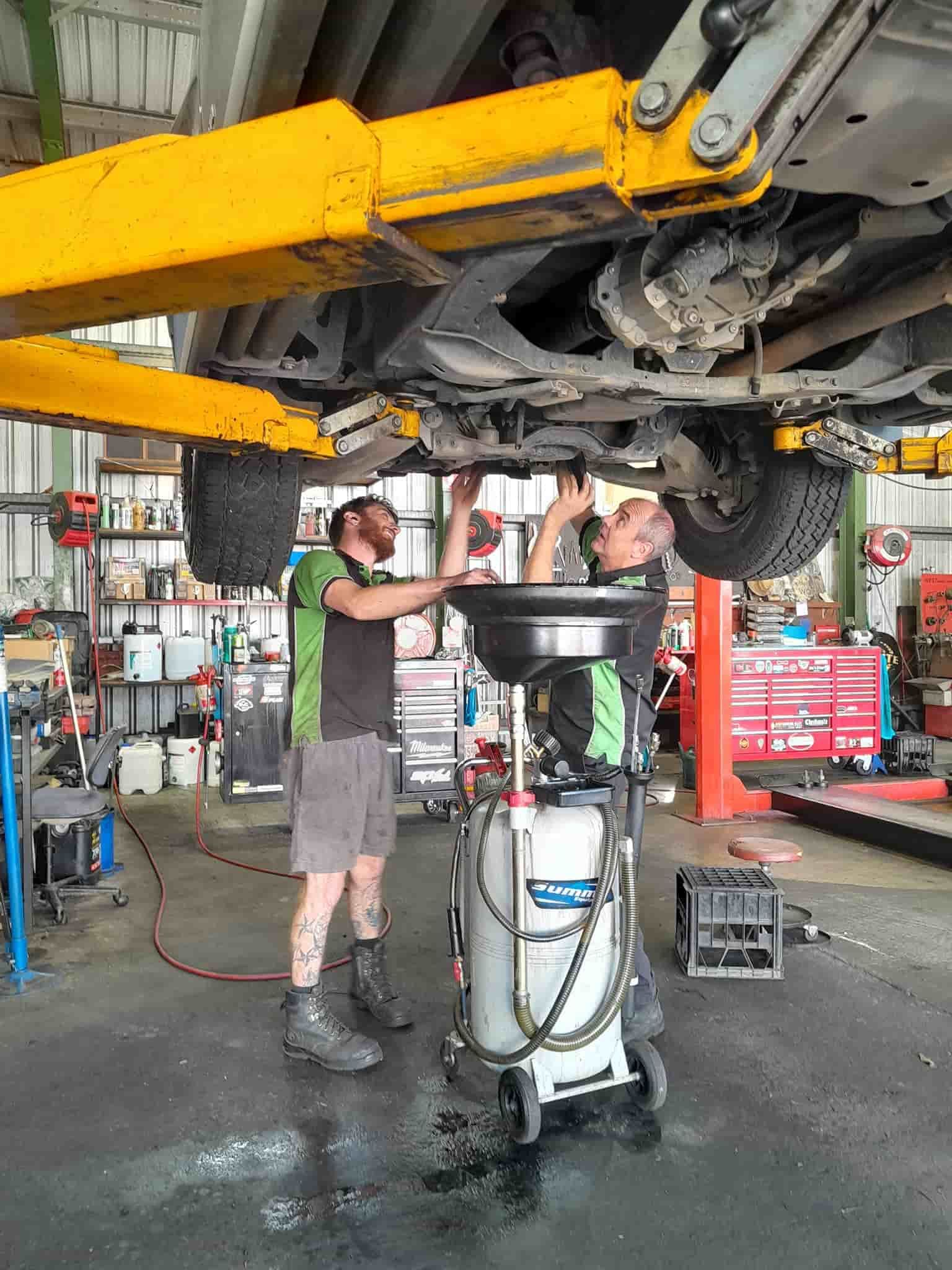 Two Men Are Working Under a Car in a Garage — CB Automotive In Yatala, QLD