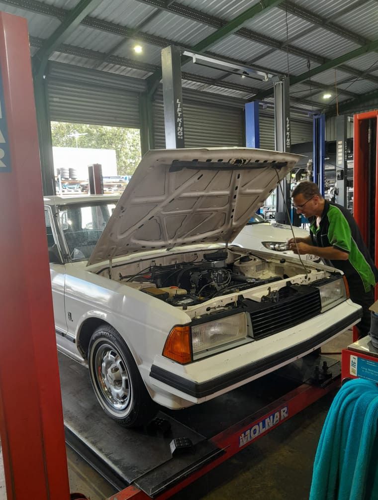 A Man is Working on a White Car in a Garage — CB Automotive In Yatala, QLD