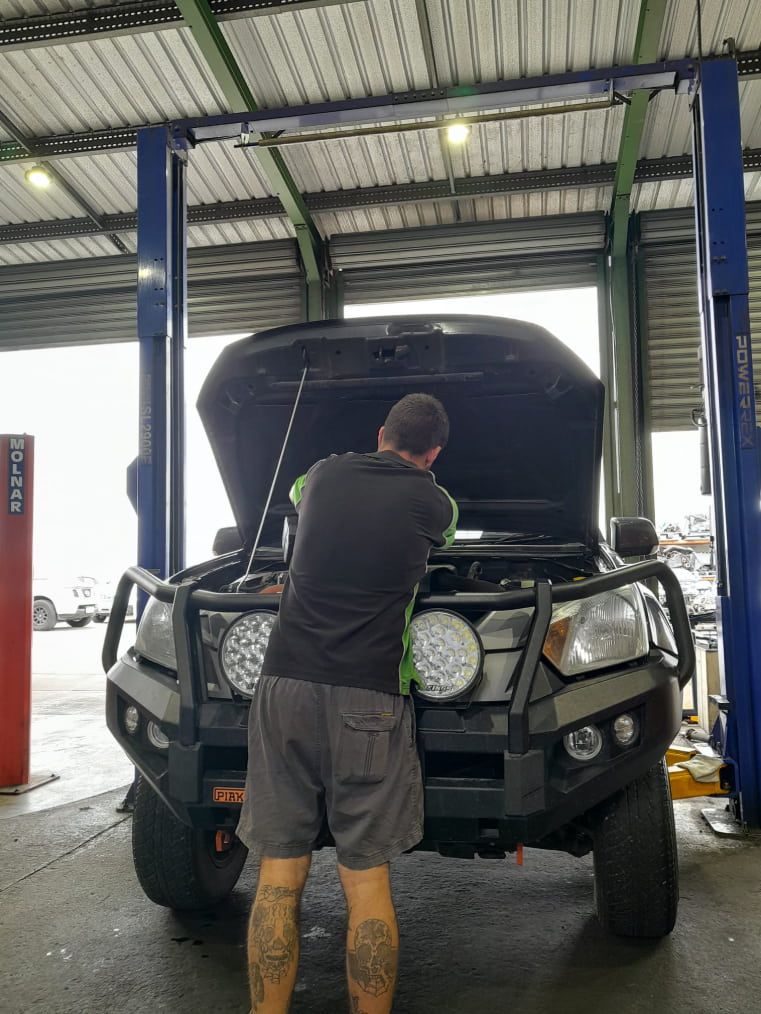 A Man is Working on the Hood of a Truck in a Garage — CB Automotive In Yatala, QLD