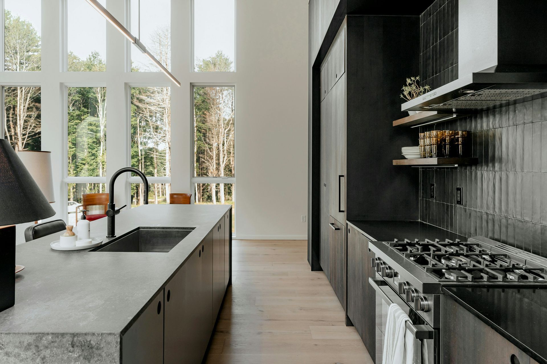 A kitchen with a large island , stove , sink and lots of windows.