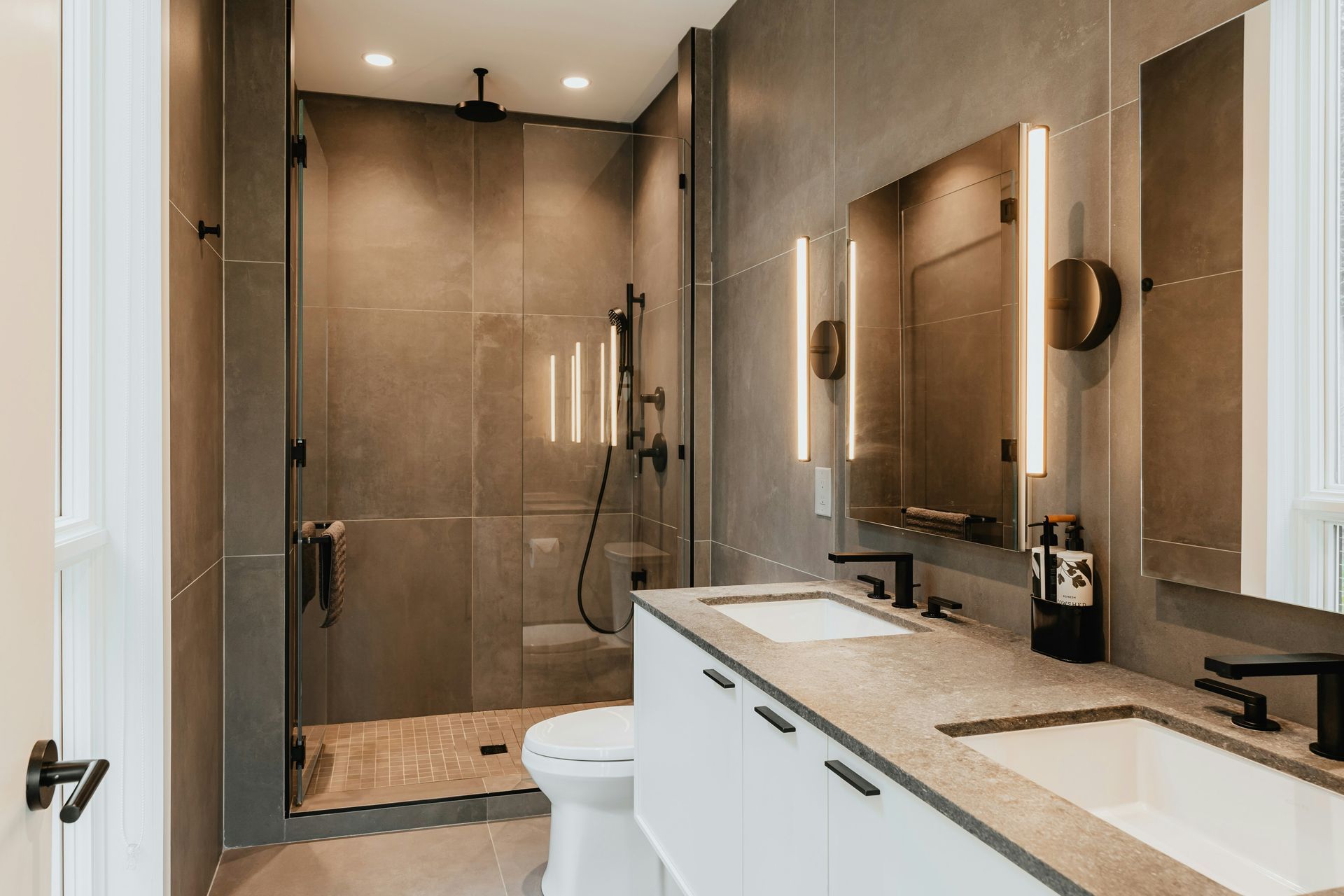 A bathroom with a toilet , sink , shower and mirror.