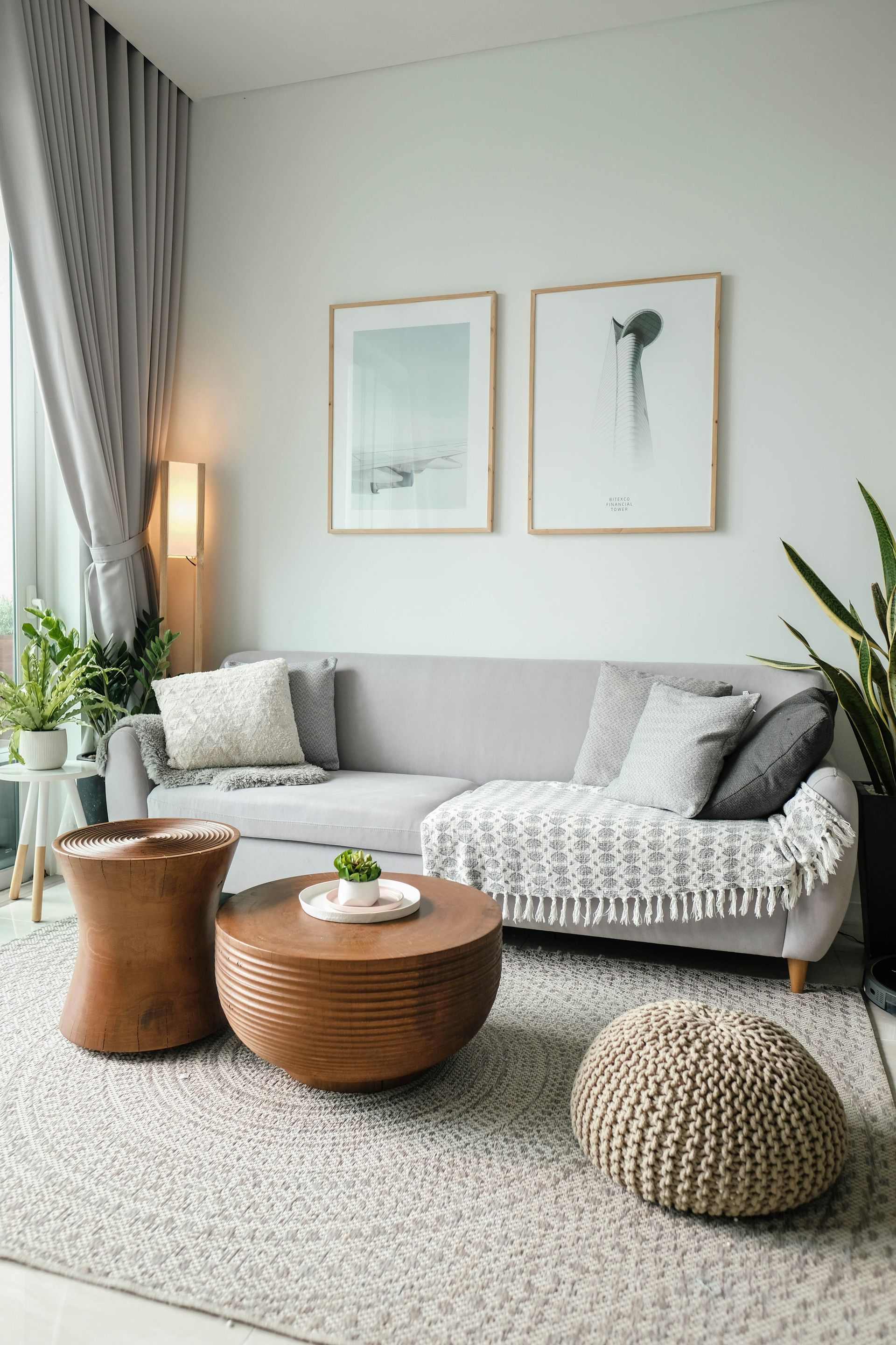 A living room with a couch , two coffee tables , and two pictures on the wall.