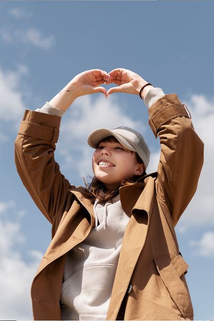 A woman is making a heart shape with her hands.