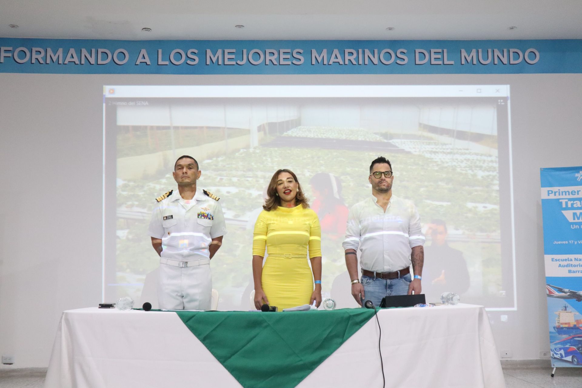 Un grupo de personas de pie alrededor de una mesa frente a una pantalla de proyector.