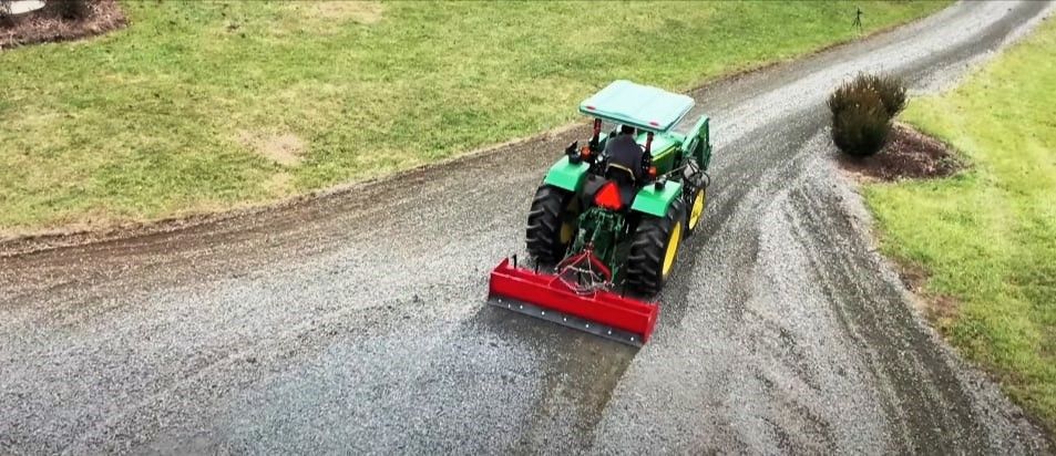 Tractor grading a curved gravel driveway.