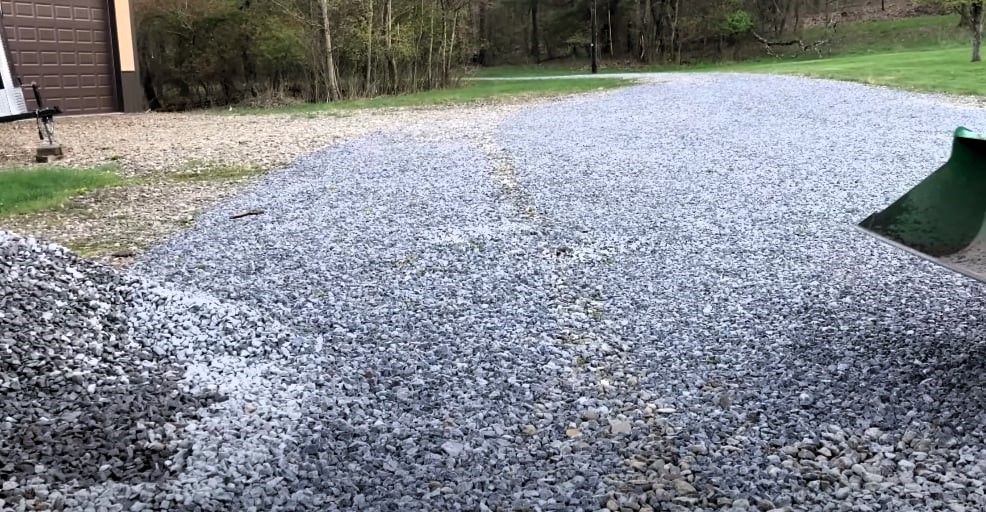 Gravel driveway with grass edges and a green object on the right.