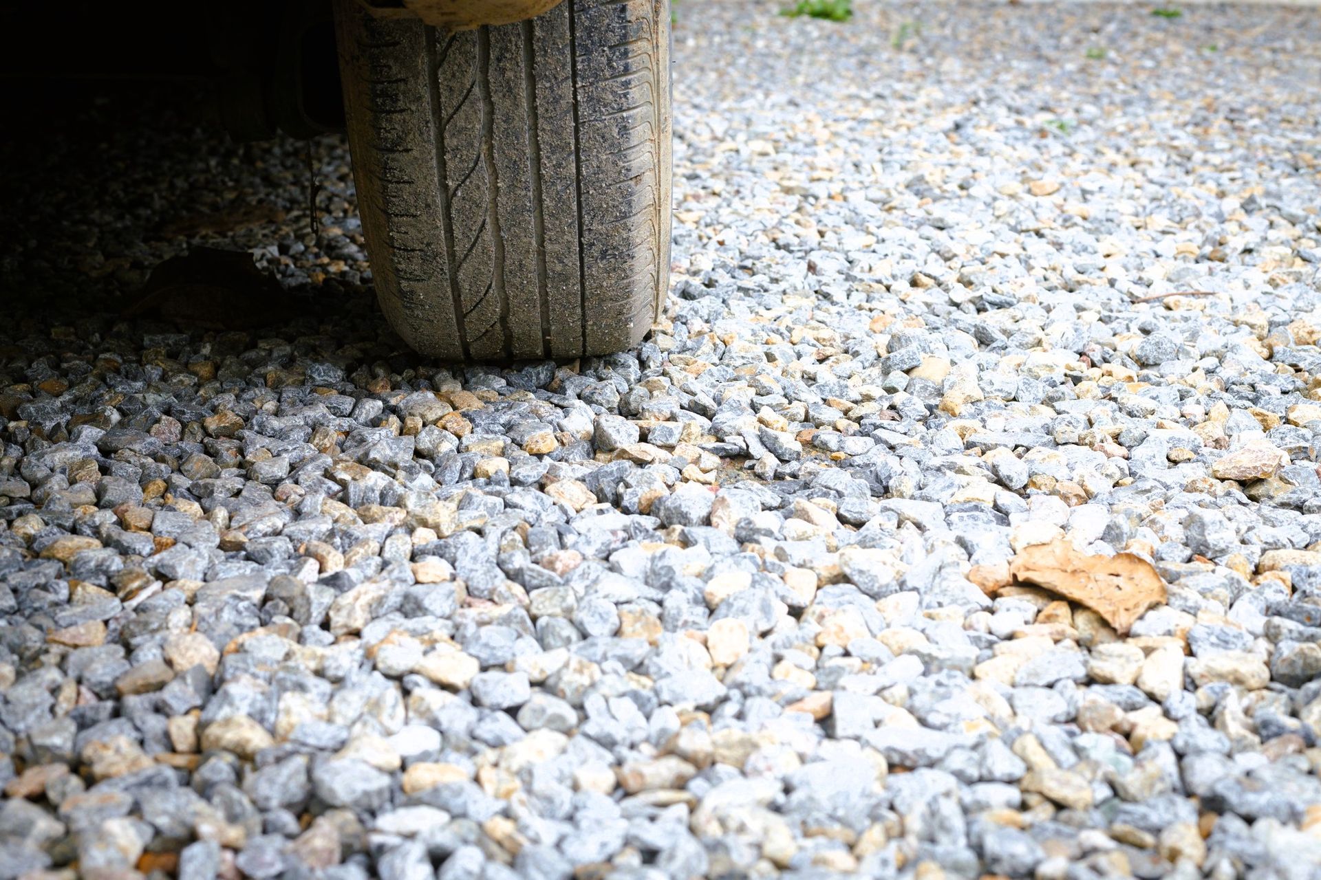 Car tire on a gravel surface with visible treads and small stones.