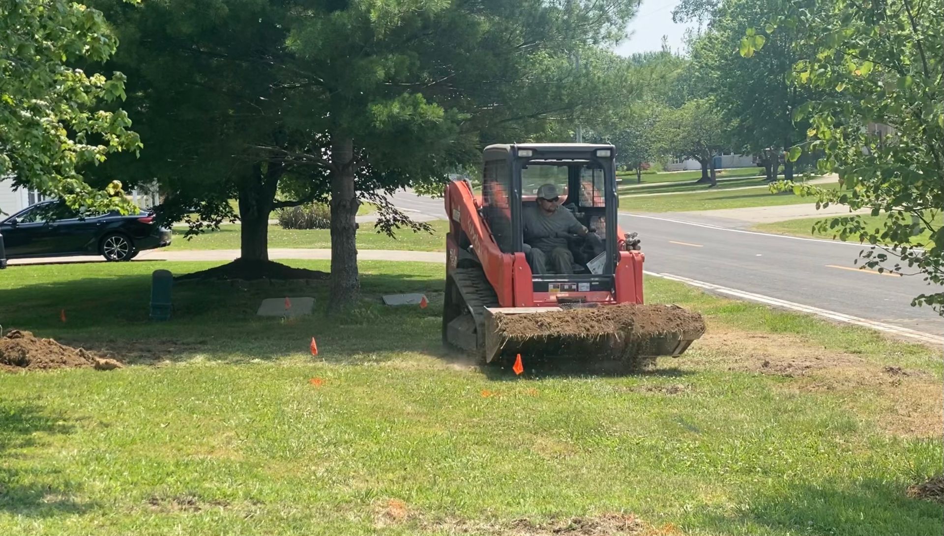 A man is driving a red bulldozer on a lush green field.