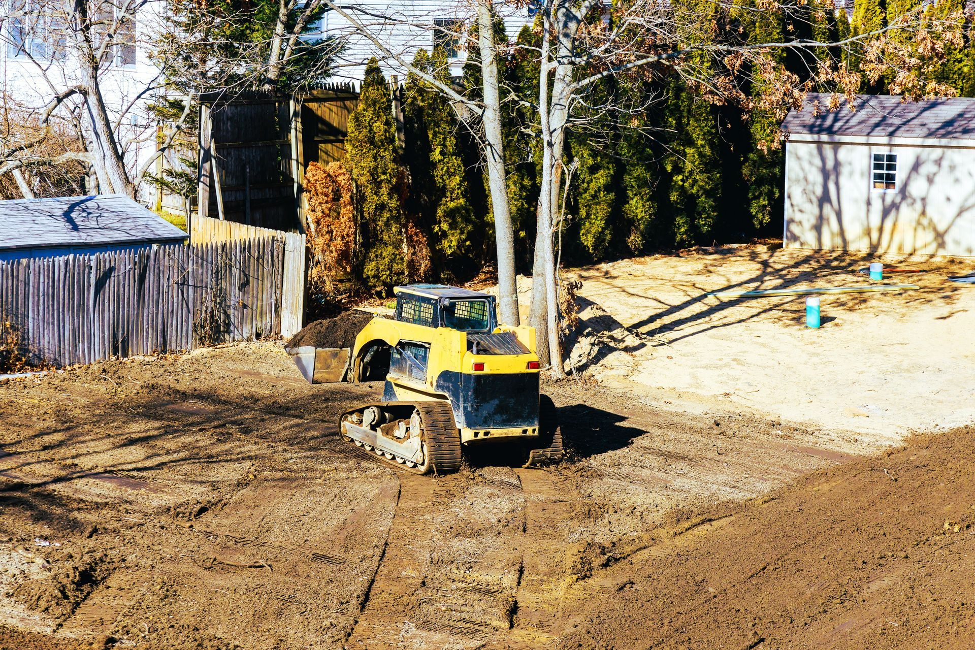 A bulldozer grading land near a home, preparing the area for landscaping or construction.