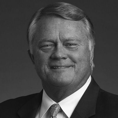 A man in a suit and white shirt is standing with his arms crossed.