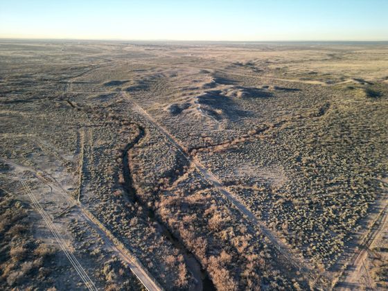 An aerial view of a dirt road in the middle of a desert.