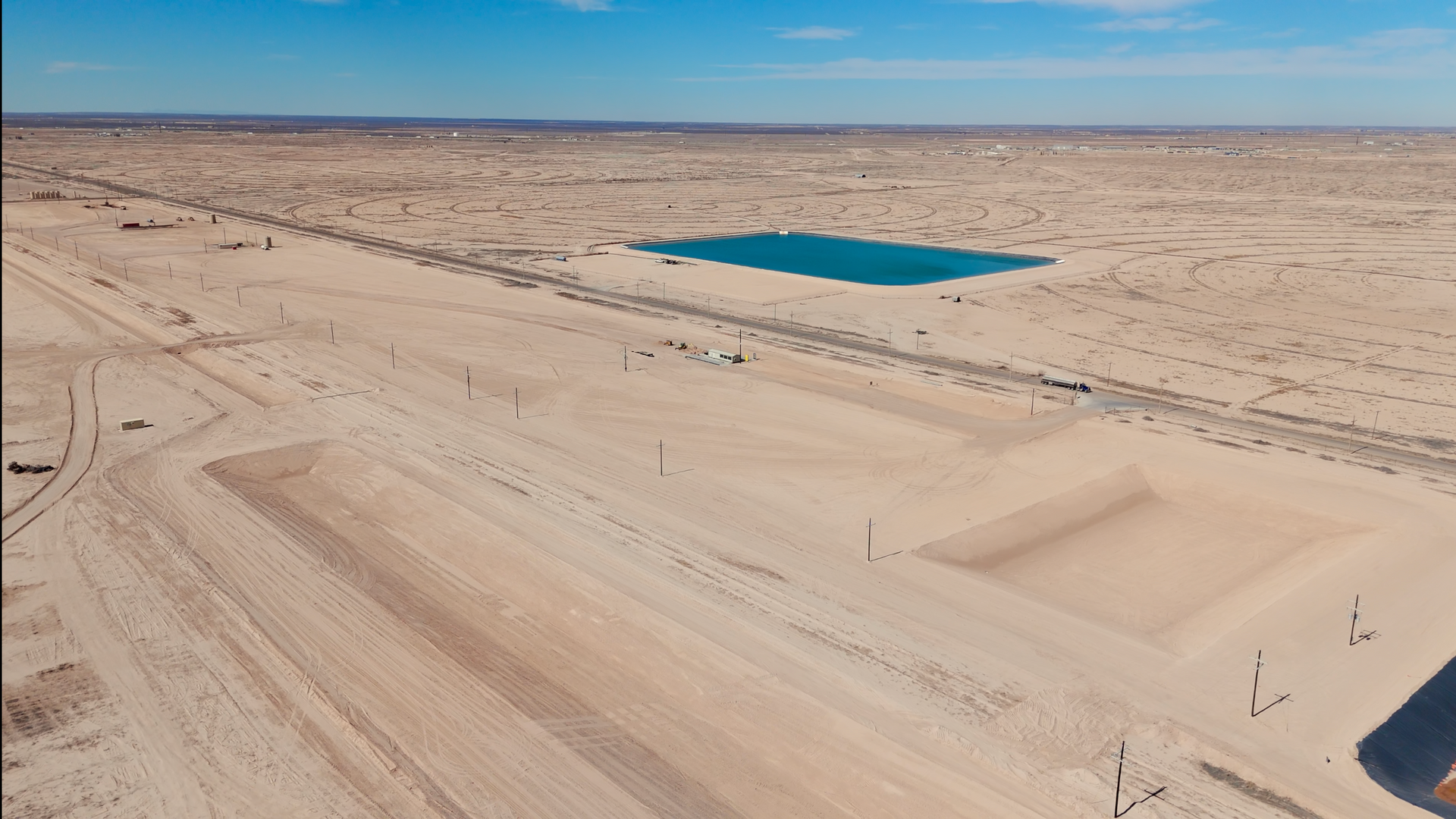 An aerial view of a desert with a small pond in the middle