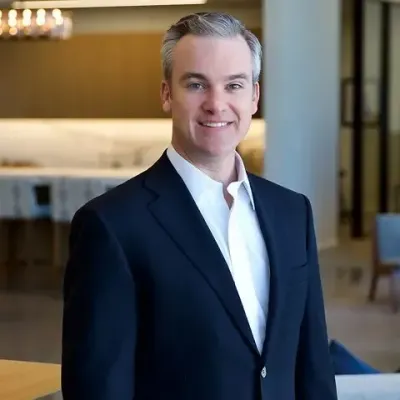 A man in a suit and white shirt is standing with his arms crossed.