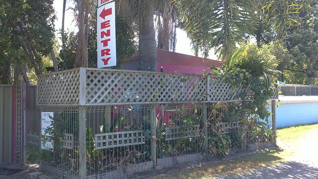 A fence with a sign that says entry is surrounded by trees.