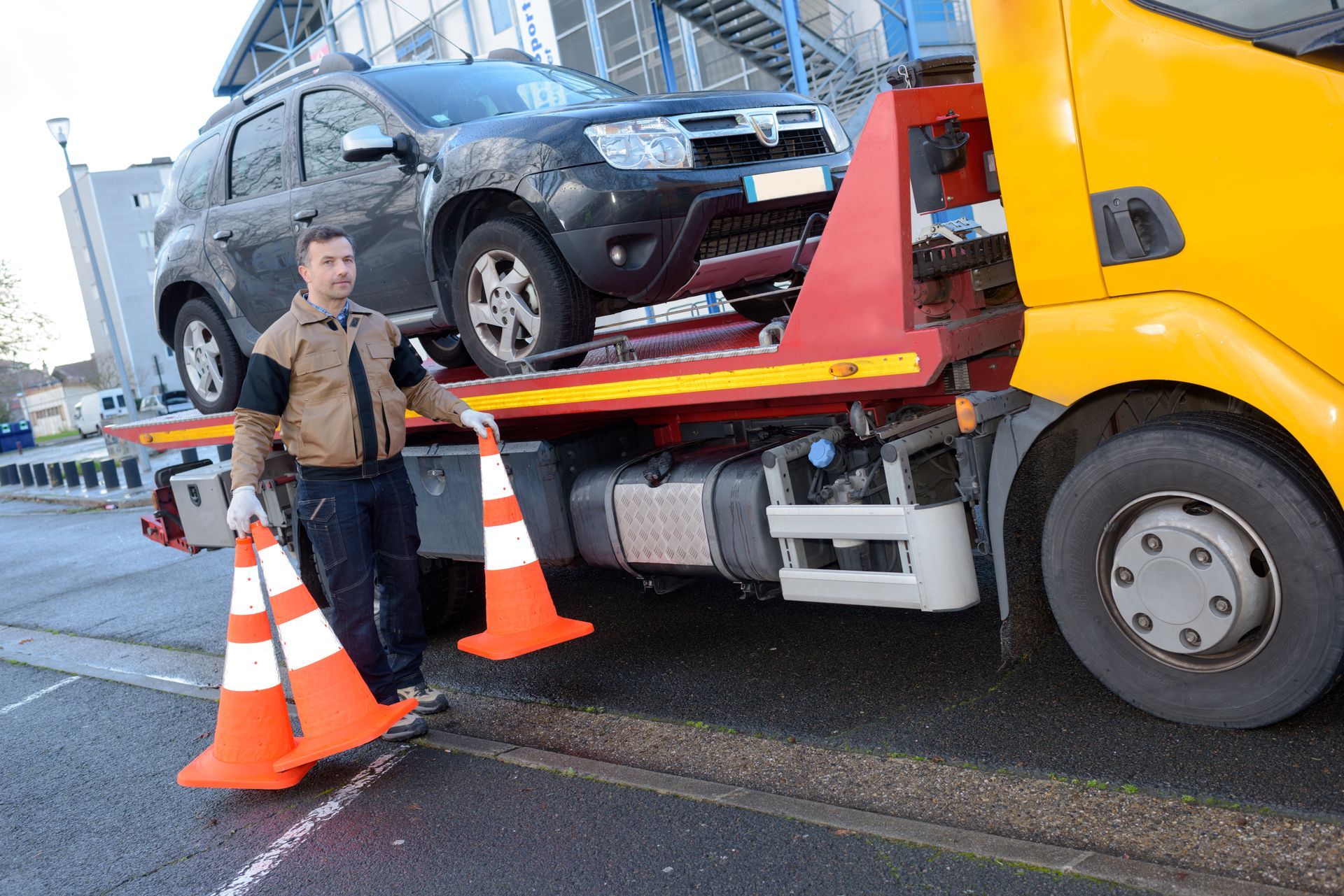 Tow truck operator preparing to tow a silver car on a sunny day.