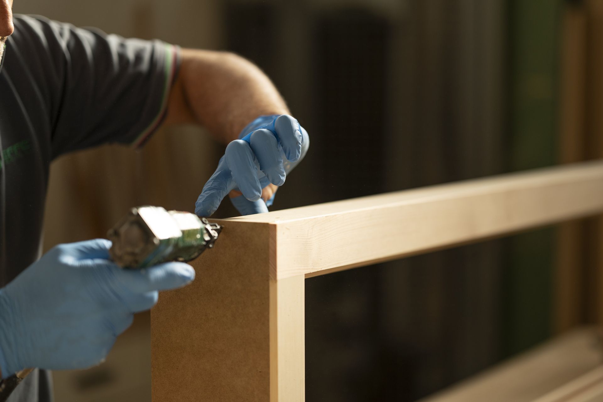 Una persona che indossa guanti blu applica la colla alla cornice di legno.