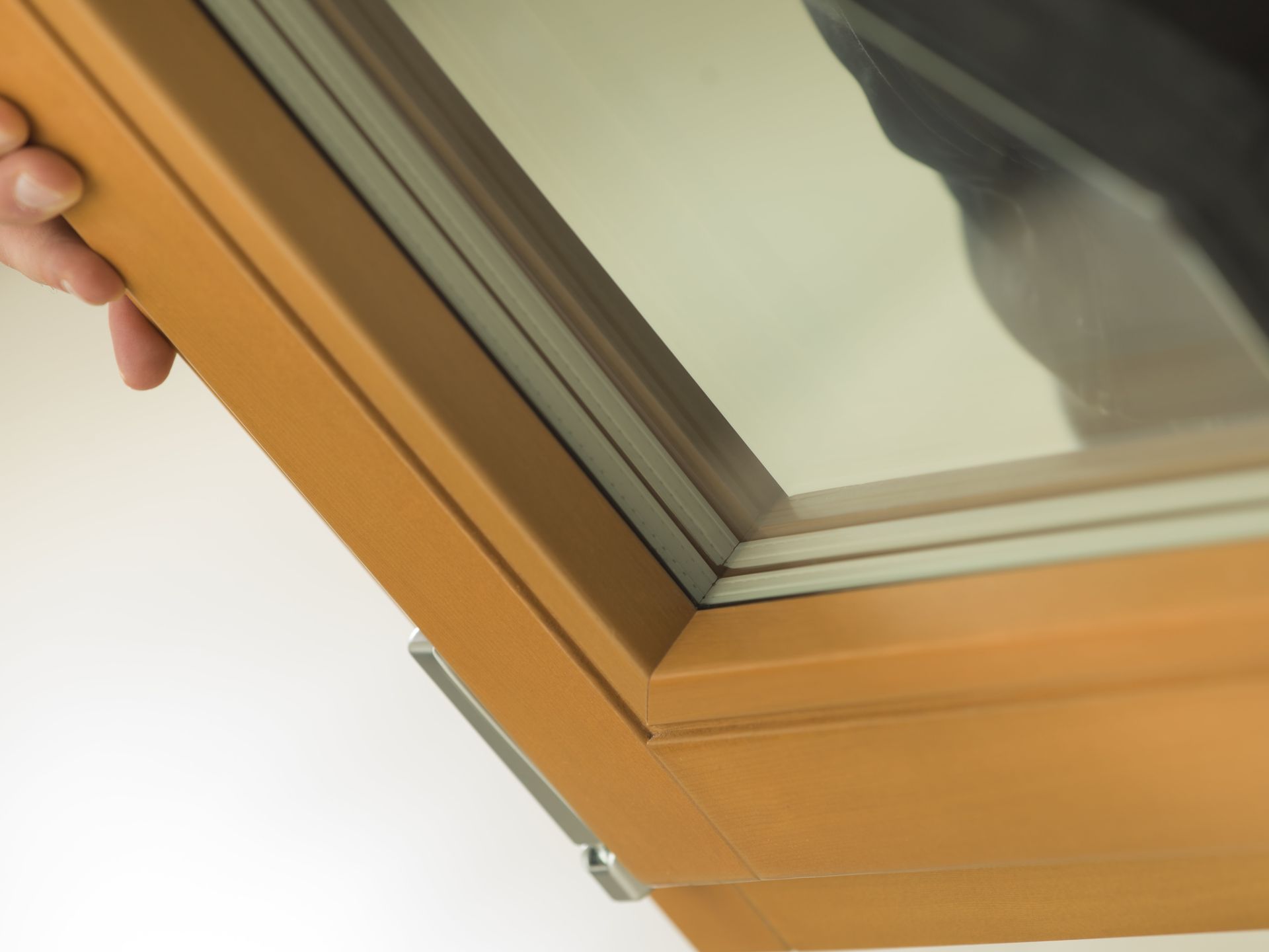 Una persona tiene aperto il telaio di una finestra marrone chiaro, rivelando più pannelli di vetro.