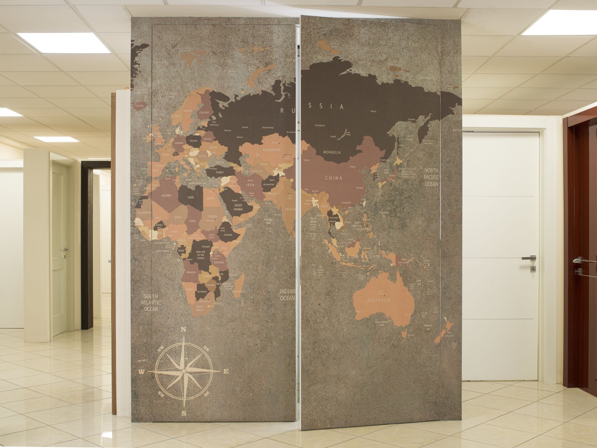 Porta a due pannelli con motivo raffigurante una mappa del mondo nelle tonalità del marrone e del grigio; in uno showroom.