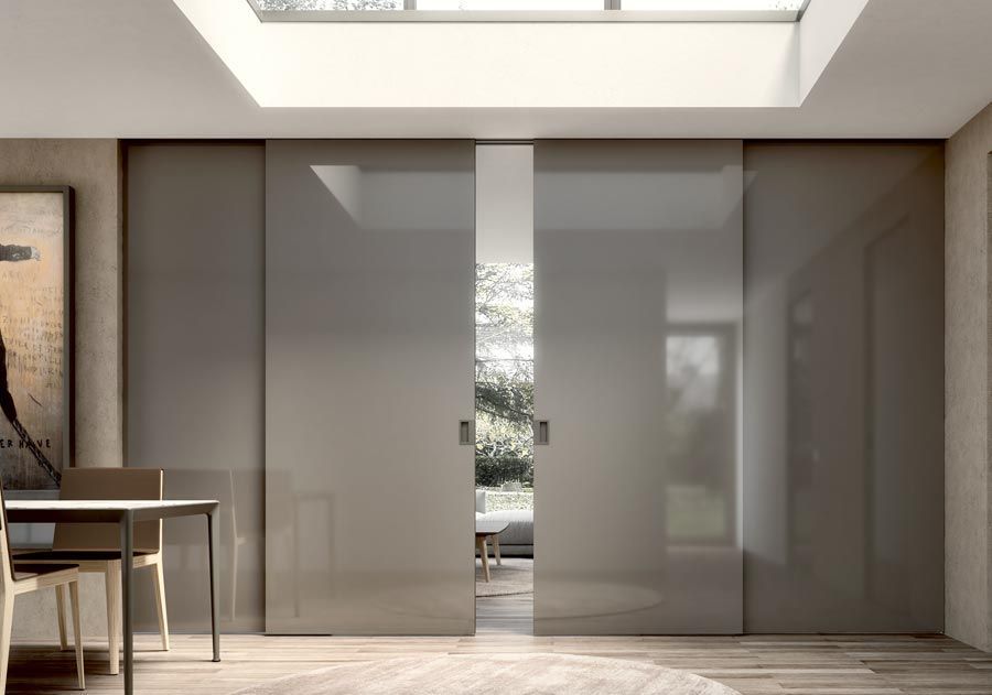 Le porte scorrevoli grigie si aprono su una vista esterna soleggiata. 