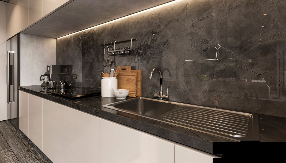Cucina moderna con ripiani scuri, mobili bianchi e paraschizzi grigio.