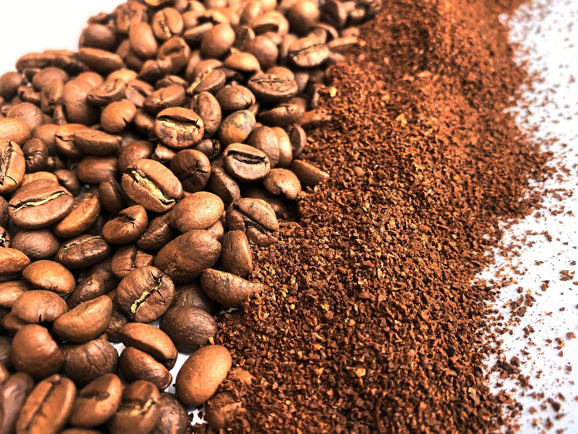 A pile of coffee beans next to a pile of ground coffee.