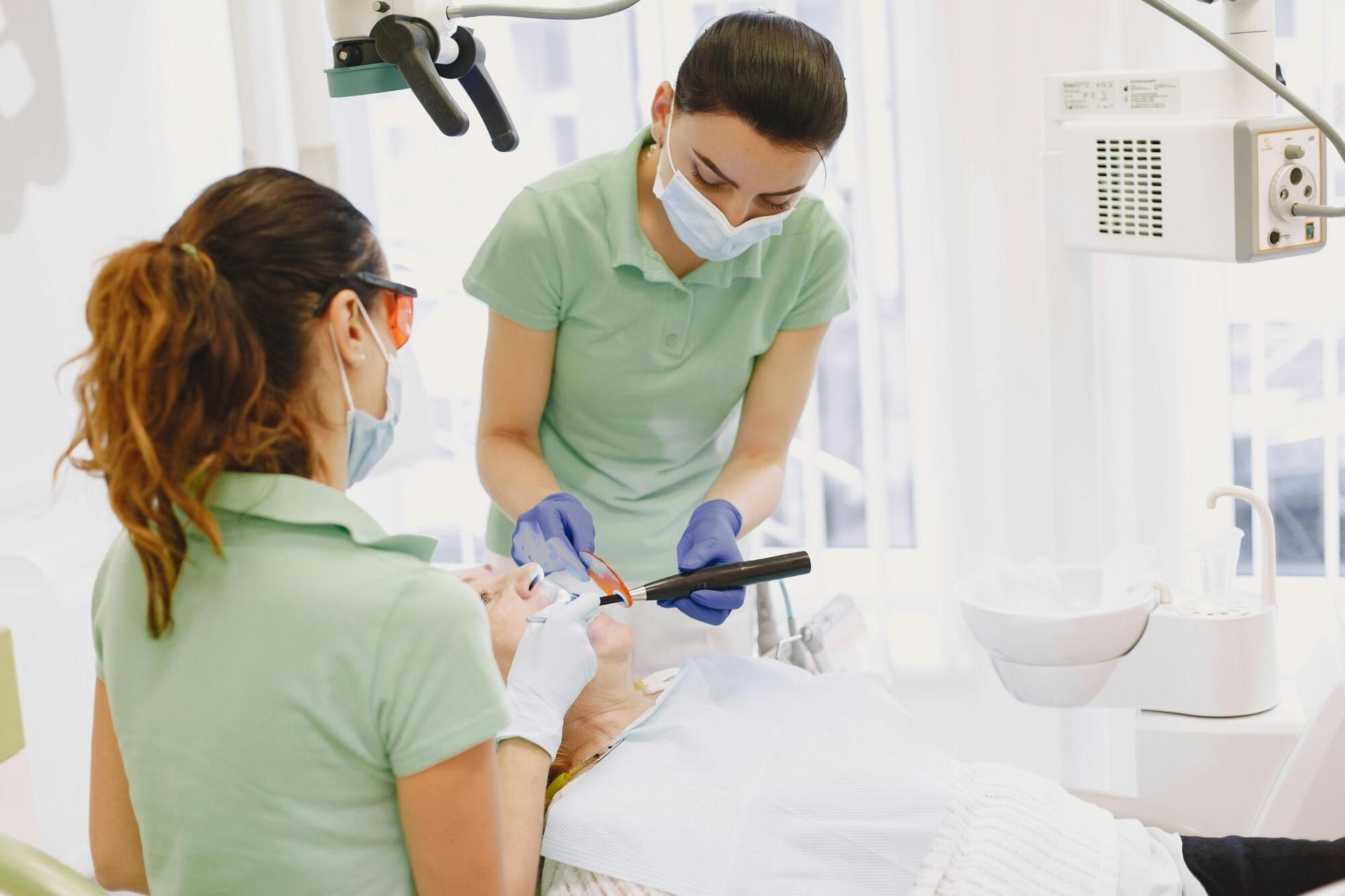Two dental professionals attending to a patient in a dental chair.