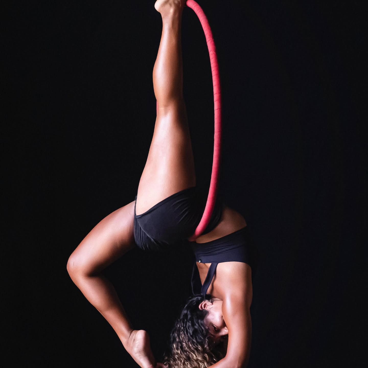 A woman is doing a handstand on an aerial hoop