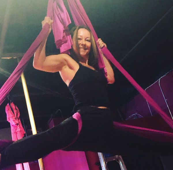 A woman in a black tank top is hanging from a pink cloth