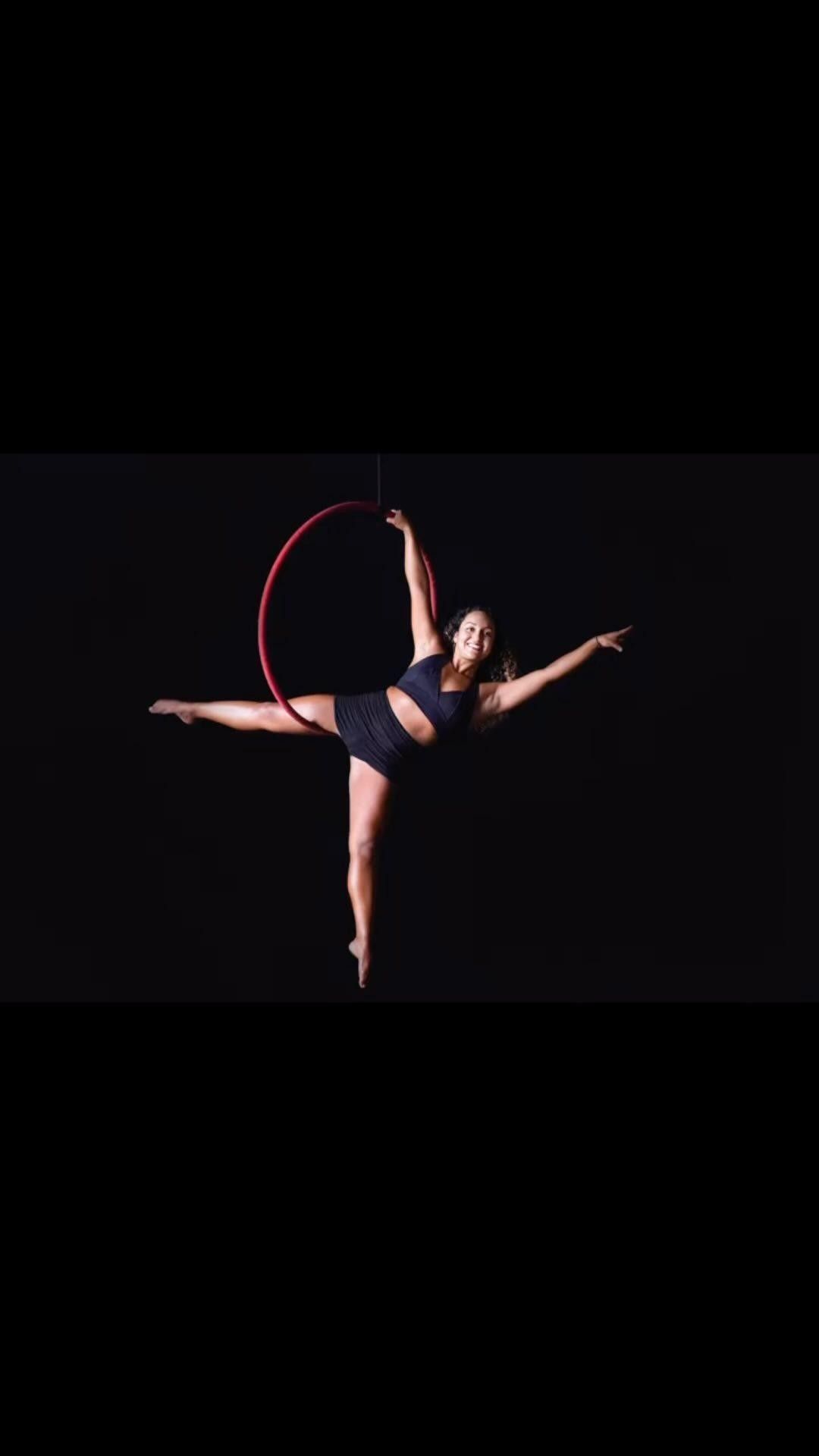 A woman is doing aerial acrobatics with a hula hoop.