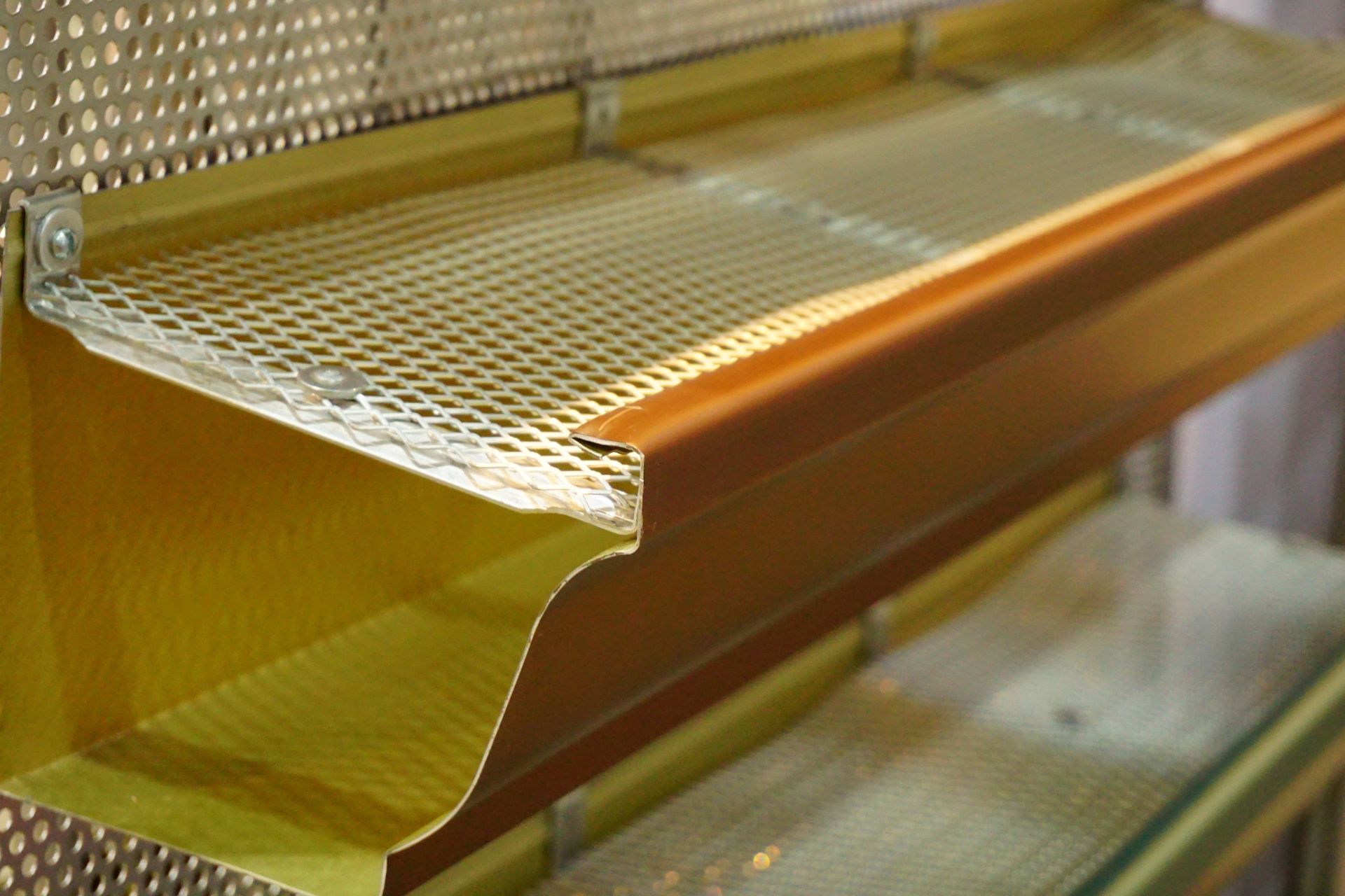 Close-up of a gold gutter with a metal mesh screen.