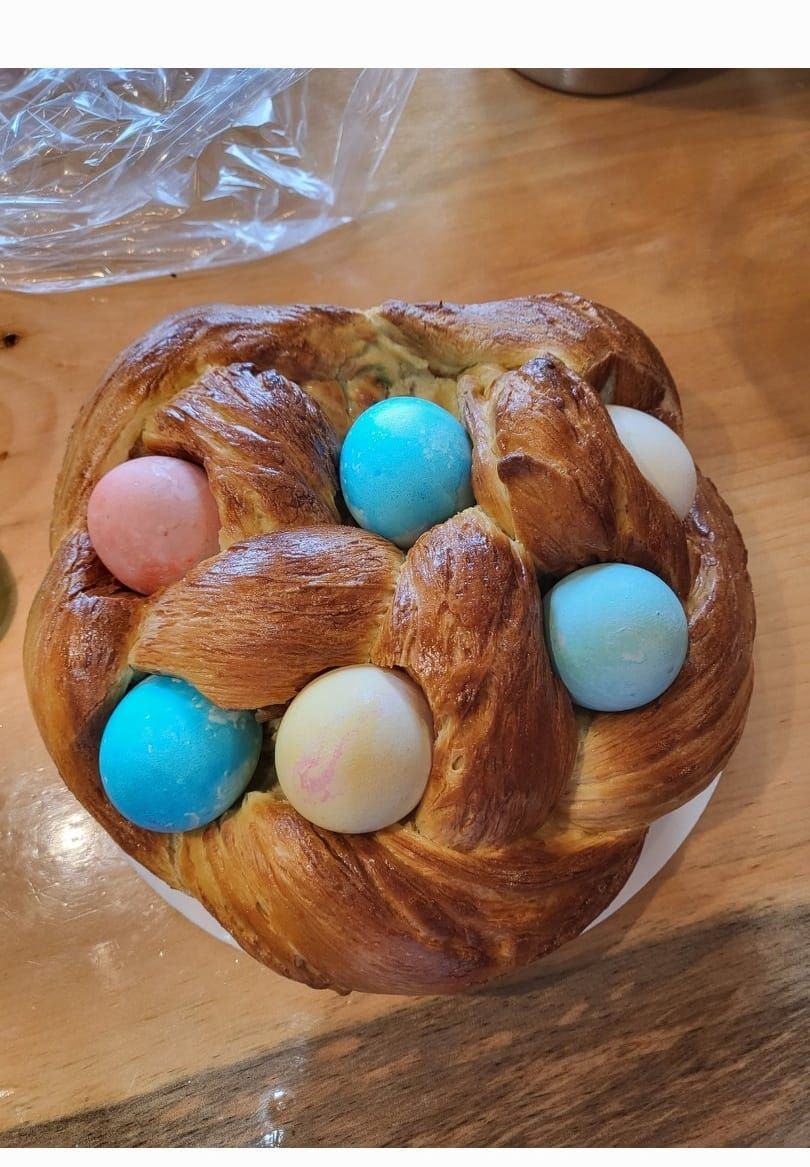 A loaf of bread with easter eggs in it on a wooden table.