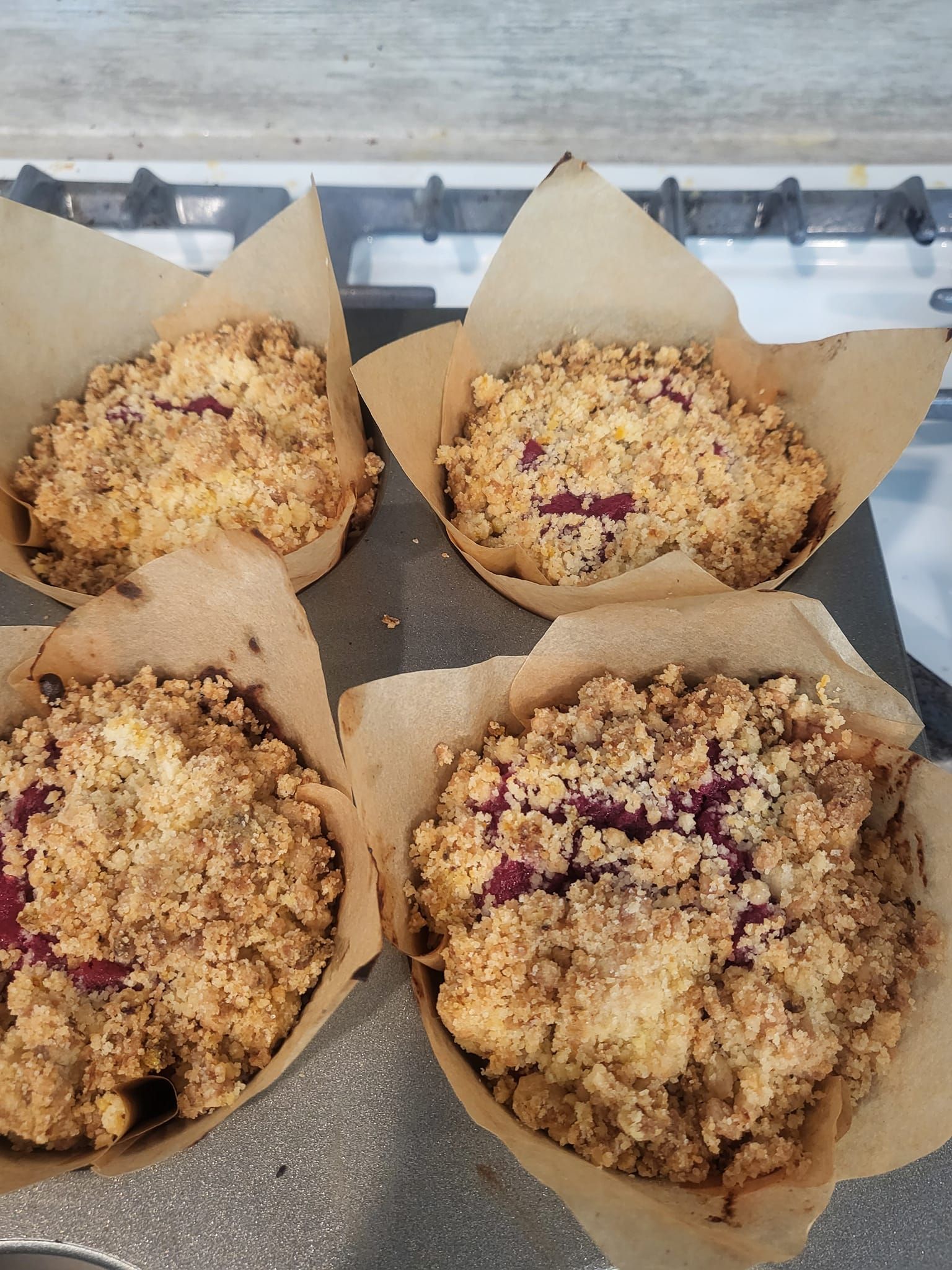Four muffins are sitting on top of a stove.