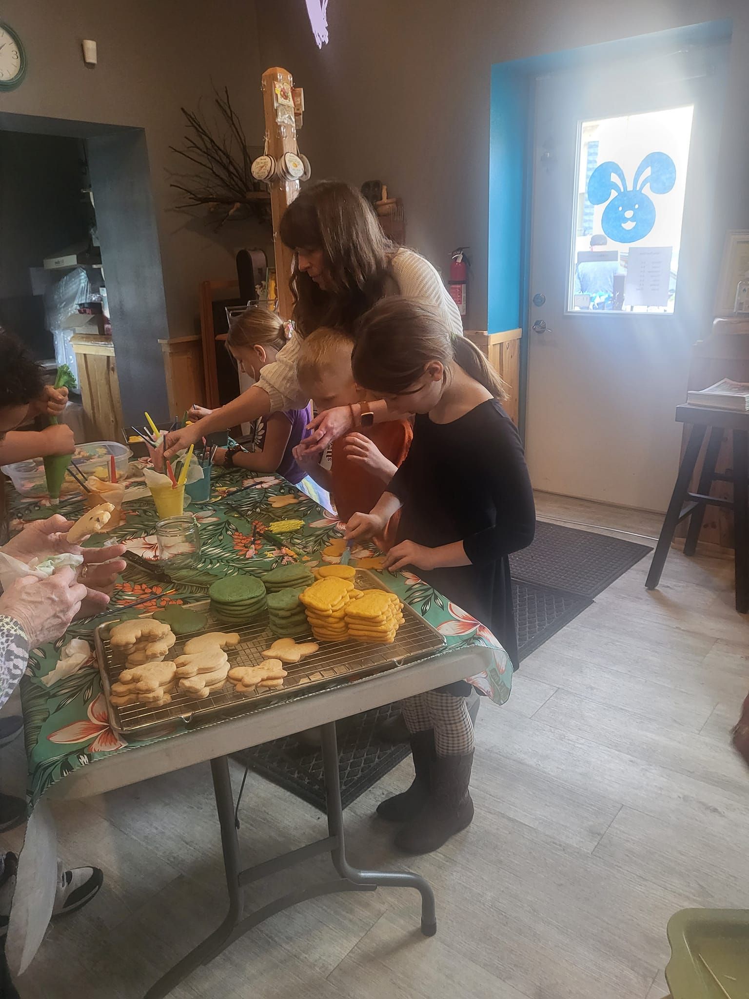 A group of children are sitting at a table decorating cookies.