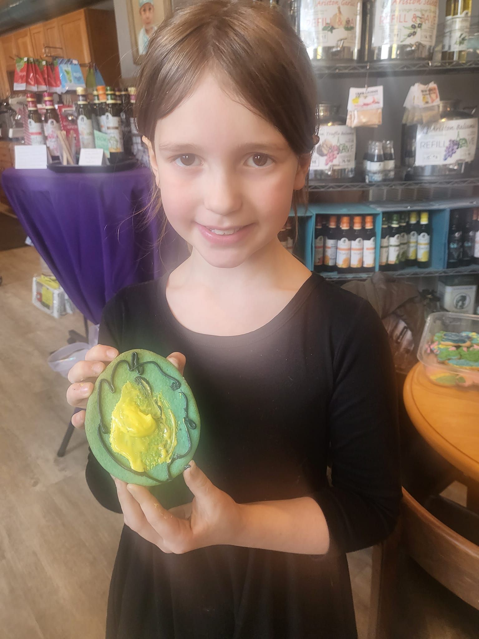 A young girl is holding a green bowl with a yellow frog on it.