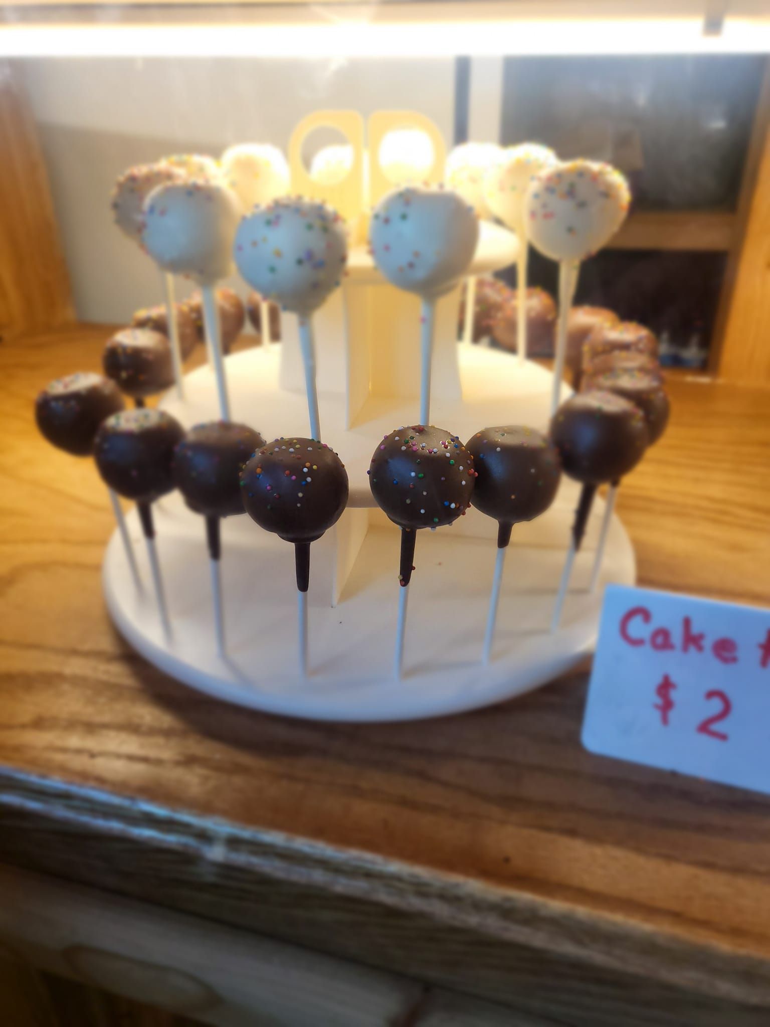 A display of cake pops with a sign that says cake pops $ 2