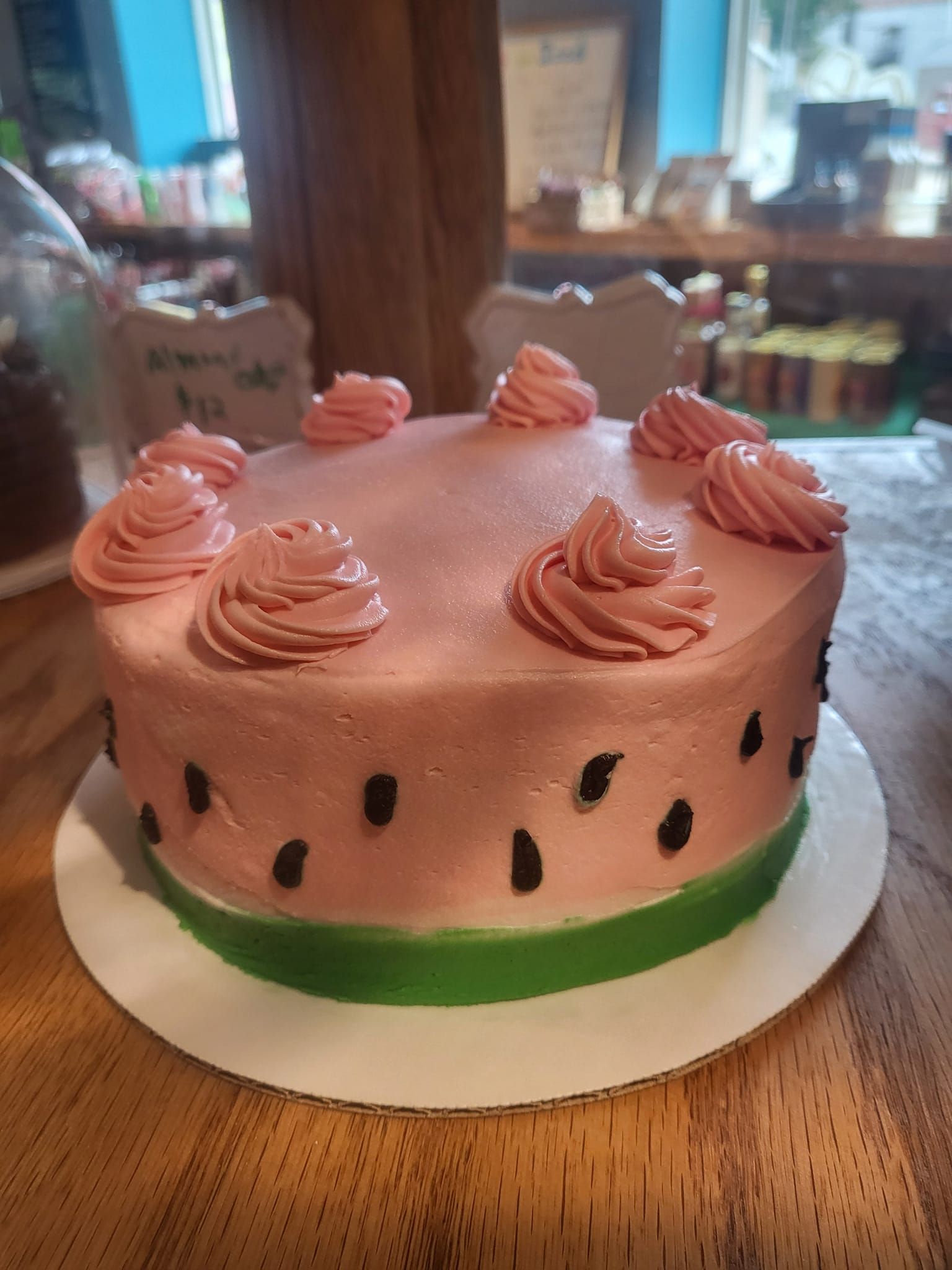 A watermelon cake is sitting on a wooden table.