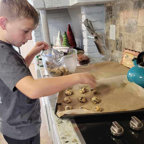 A young boy is preparing cookies in a kitchen