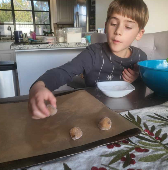 A young boy is sitting at a table with a bowl of food