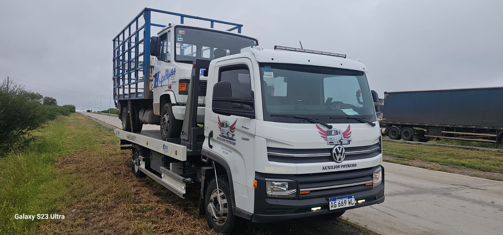 Una grúa blanca está estacionada al costado de la carretera.
