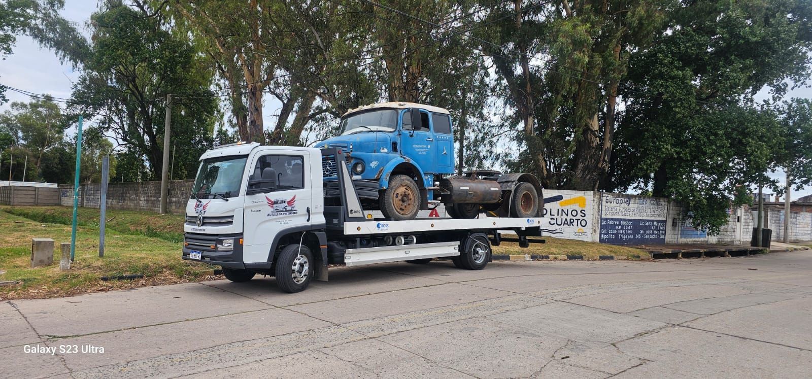 Una grúa lleva un camión azul en la parte trasera.