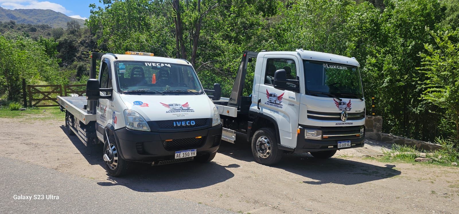 Dos grúas están estacionadas una al lado de la otra en un camino de tierra.