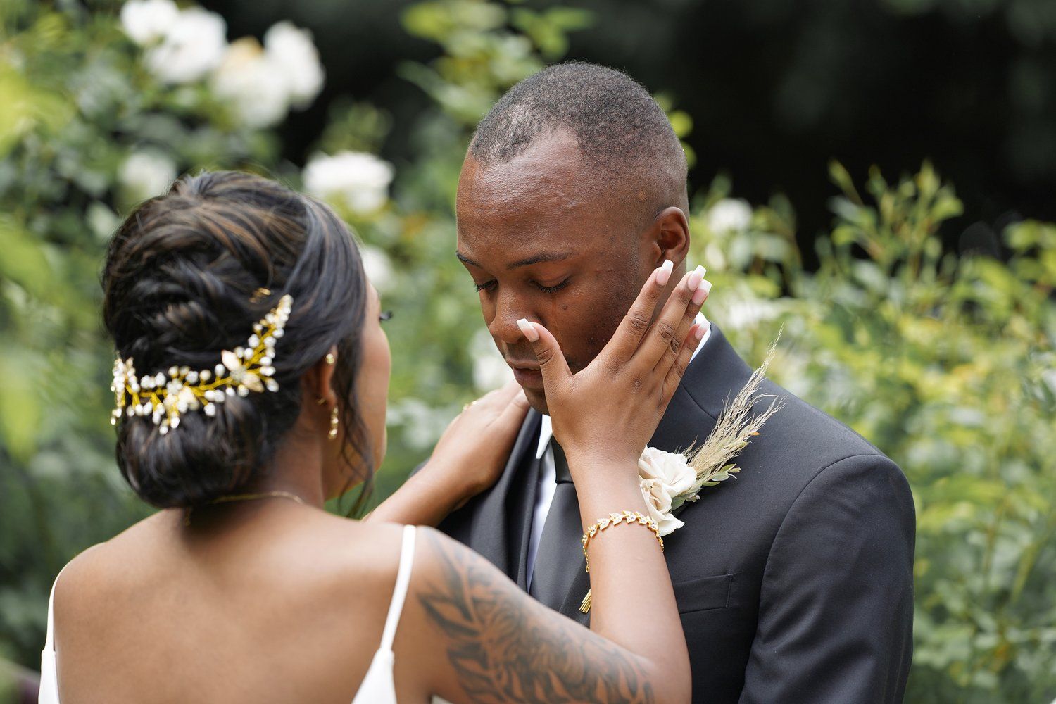 A bride and groom are looking at each other and the bride is touching the groom 's face.