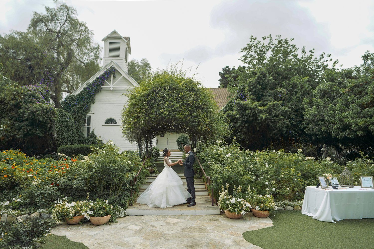 A bride and groom are standing in front of a small white church.